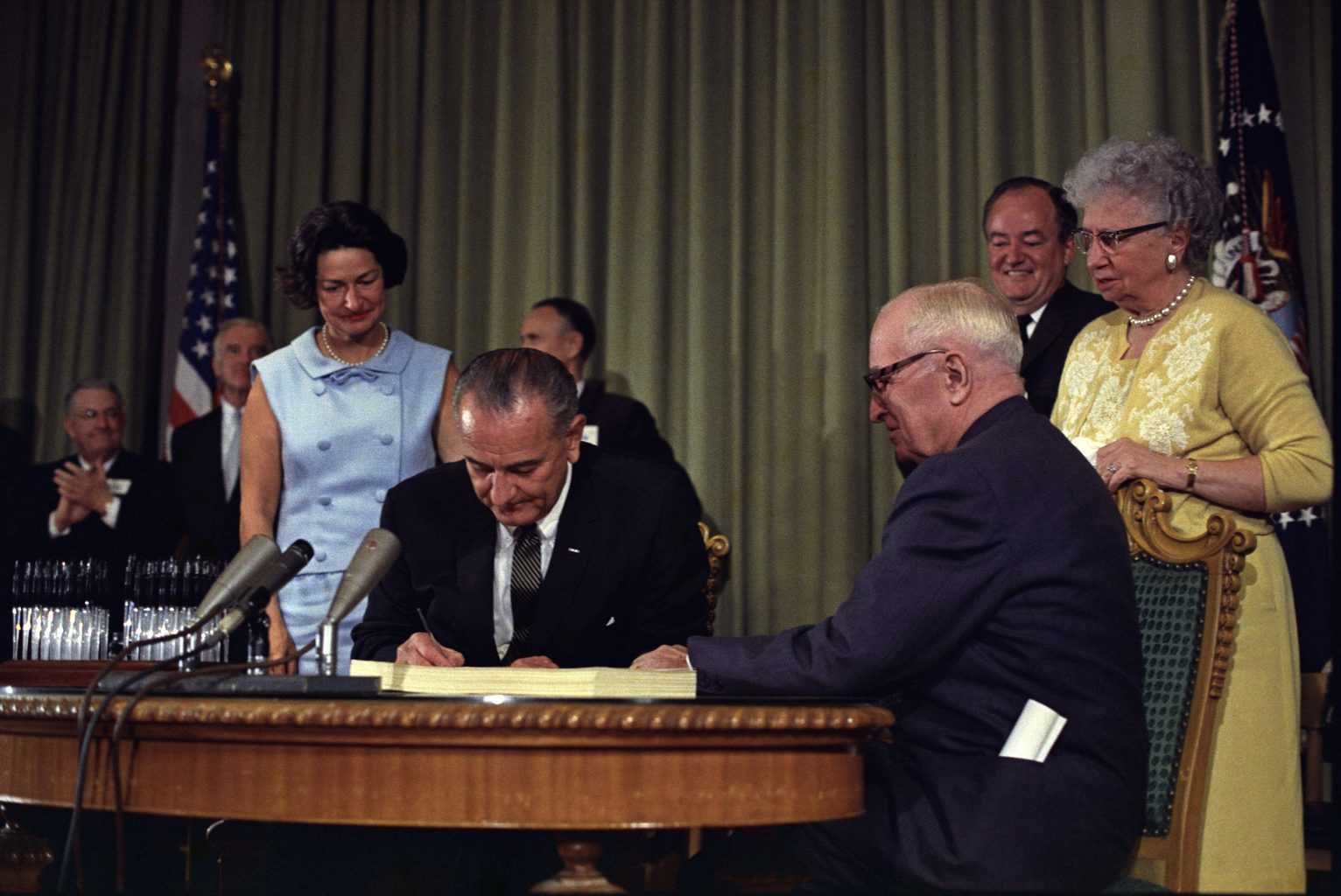Lyndon_Johnson_signing_Medicare_bill,_with_Harry_Truman,_July_30,_1965